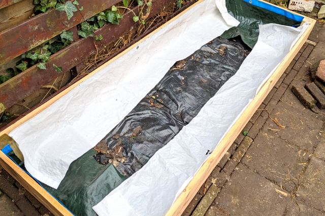 Een verhoogde bak bouwen met plastic bekleding om het hout te beschermen Een verhoogde bak bouwen met plastic bekleding om het hout te beschermen